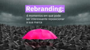 Um guarda-chuva rosa rodeado de guarda-chuvas cinzas com um céu nublado. Escrito na imagem os dizeres "Rebranding: quatro momentos em que pode ser interessante reposicionar a sua marca".